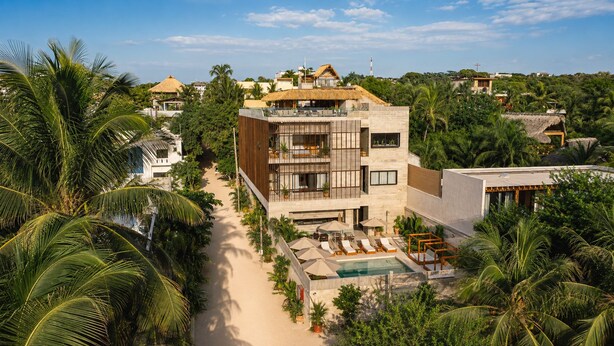 Un resort moderno con piscina, zona de estar y vegetación tropical.