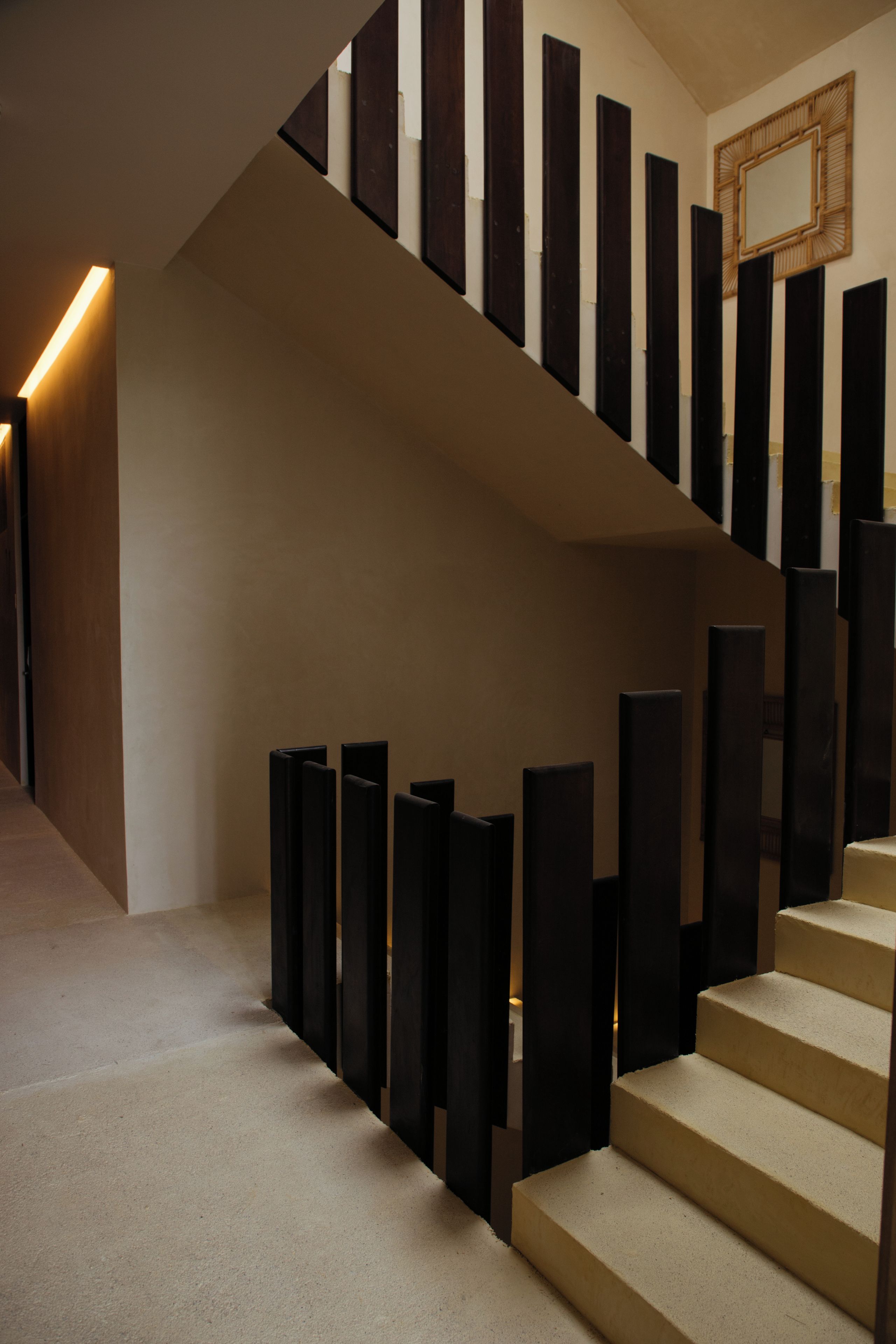A modern staircase with a geometric design, a wooden handrail, and a wall-mounted mirror.