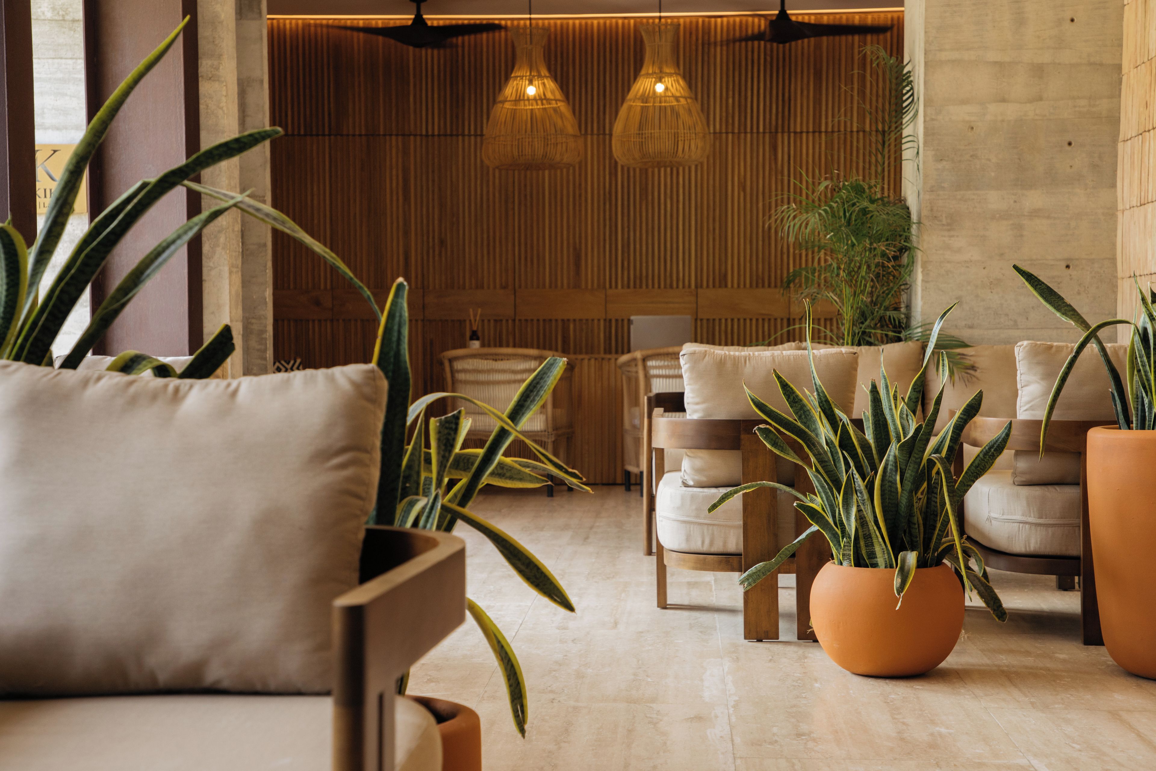 A modern interior with a seating area, wooden panel walls, and hanging pendant lights.