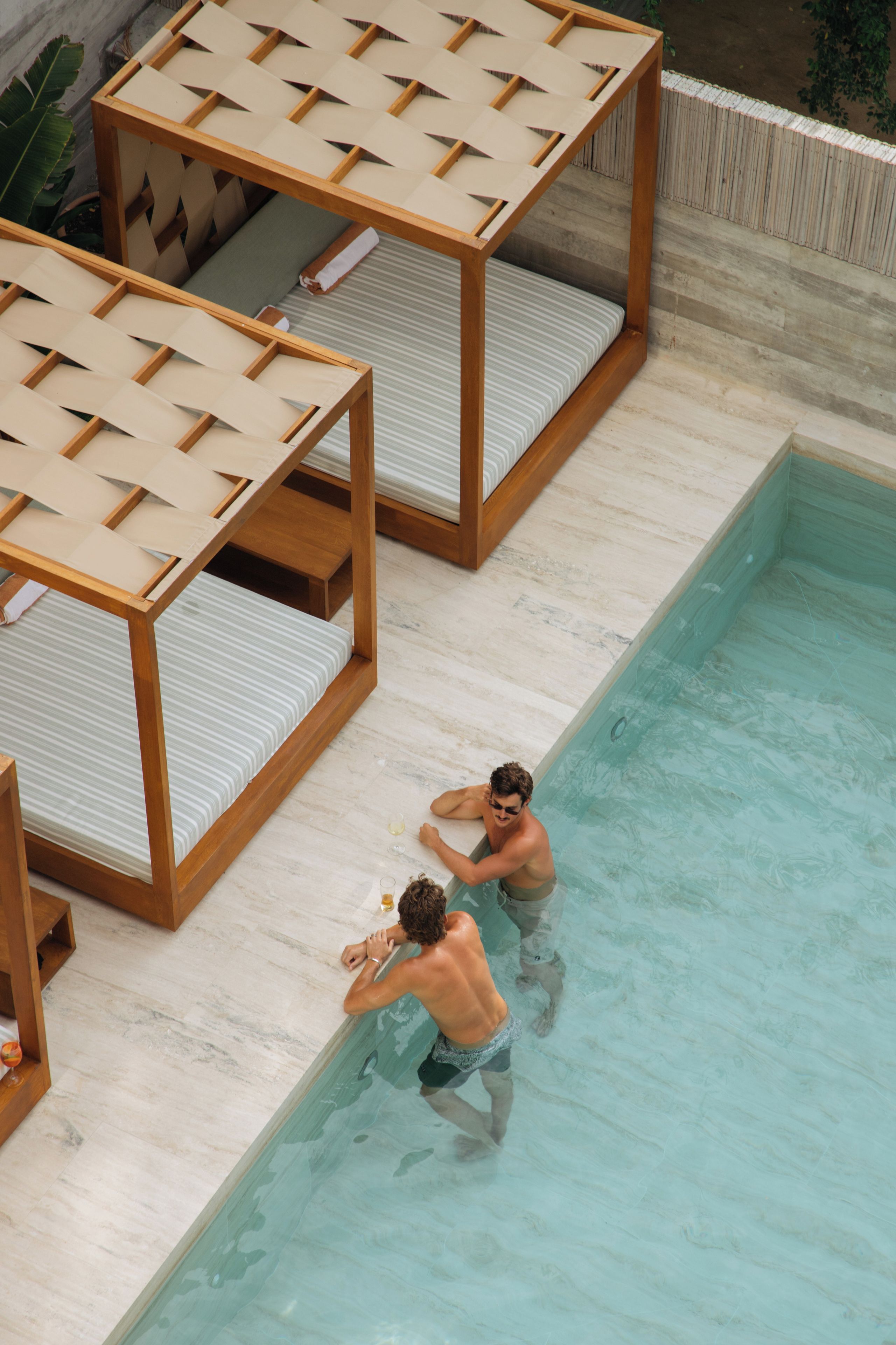 A pool area with wooden loungers and a tiled floor.