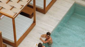 A pool area with wooden loungers and a tiled floor.
