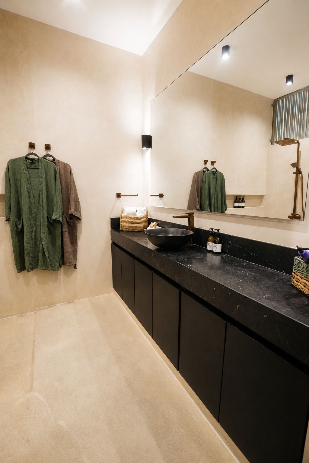 Un baño moderno con un espejo grande, un mostrador negro y un perchero con dos toallas.