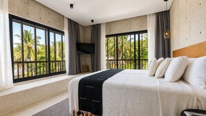Un dormitorio con una cama grande, dos ventanas con cortinas, un televisor de pantalla plana y vistas a palmeras.