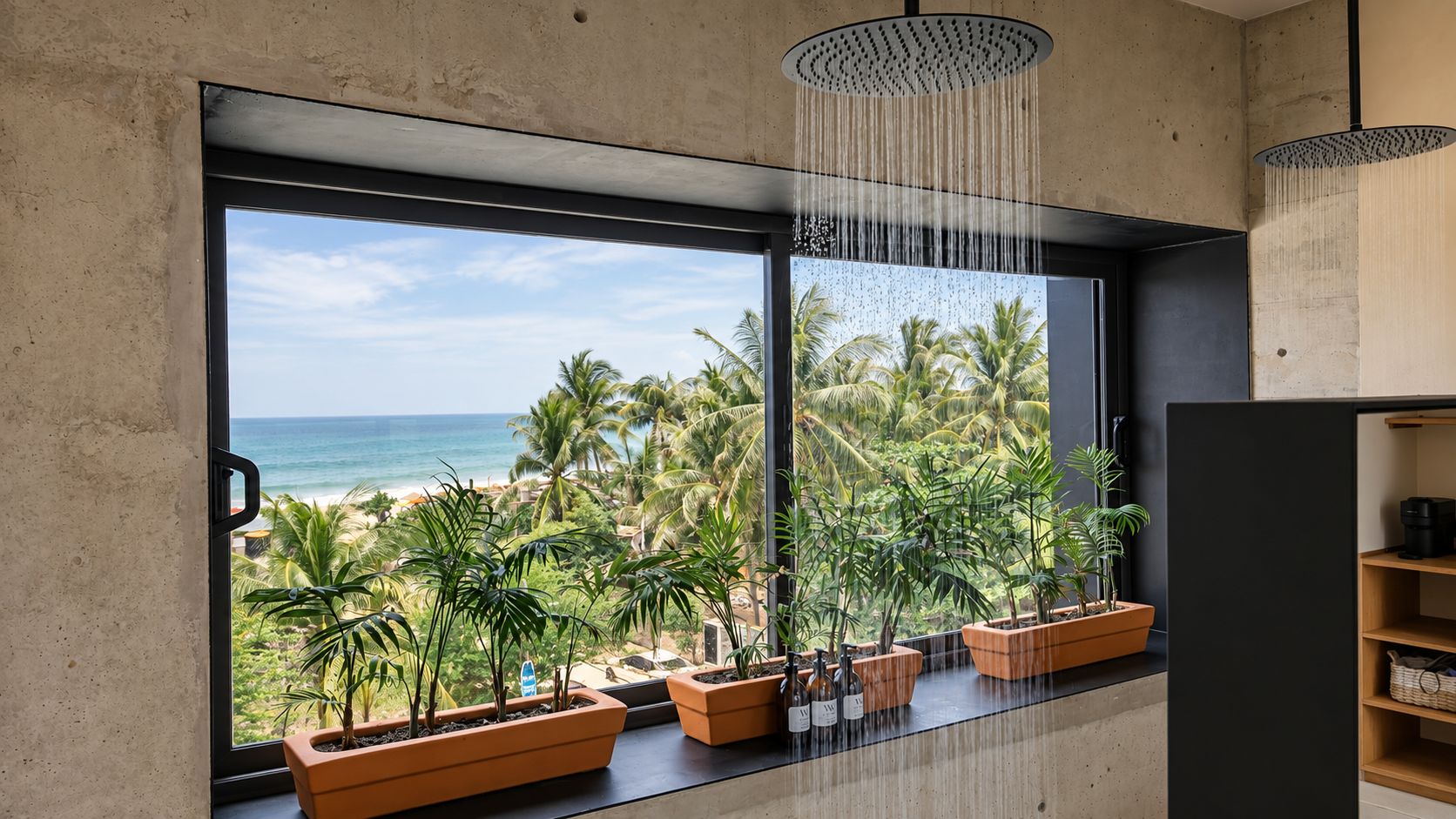 A room with a large window overlooking a beach, potted plants, and a modern shower.