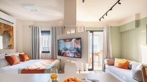 Ein Hotelzimmer mit Bett, Fernseher, Esstisch und Glas Orangensaft, mit Blick auf die Stadt.