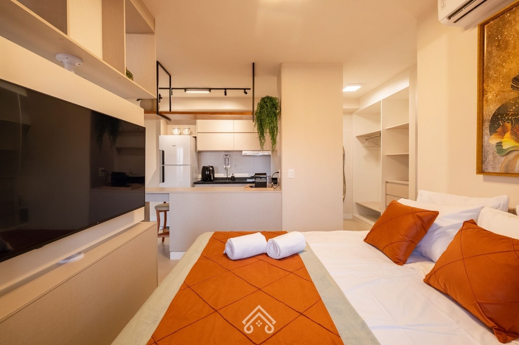 Quarto de hotel com cama, televisão, cozinha compacta e banheiro.