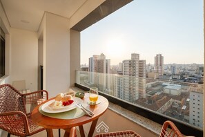 A balcony with a table set for breakfast, overlooking a cityscape. - Parking space and view in the tallest building in the city | LYVVO (Campinas)