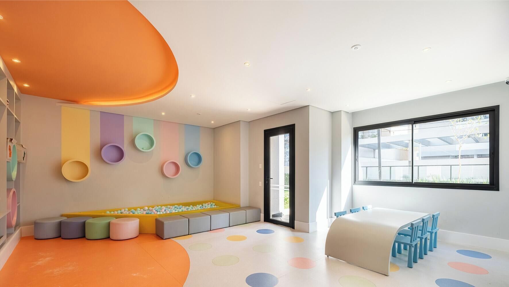 Uma sala de jogos infantil moderna com uma área de recreação colorida, um banco para sentar e uma grande janela que oferece luz natural.