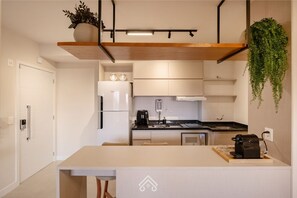 A modern kitchen with a built-in oven, a coffee machine, and a hanging plant. - Parking space and view in the tallest building in the city | LYVVO (Campinas)
