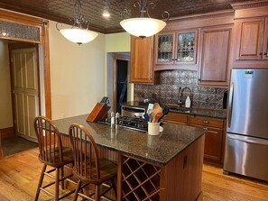 A kitchen with wooden cabinets, a stainless steel refrigerator, and a granite countertop. - This welcoming 4-bedroom house in Ouray is perfect for you. (Ouray)