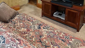 Ein Hotelzimmer mit einem Bett, einem Fernseher auf einem Holztisch und einem gemusterten Teppich.