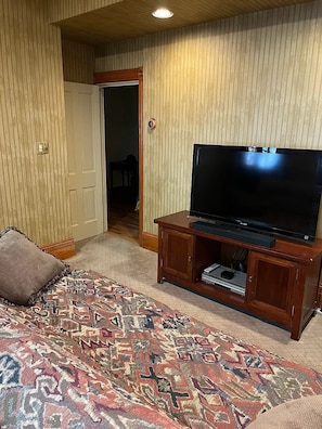 Ett hotellrum med en säng, en tv på ett träställ och en mönstrad matta.