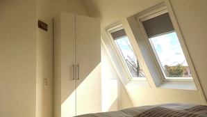 A bedroom with a skylight, a wardrobe, and a bed with a patterned bedspread. - Bendalong  Noordwijk (Noordwijk)