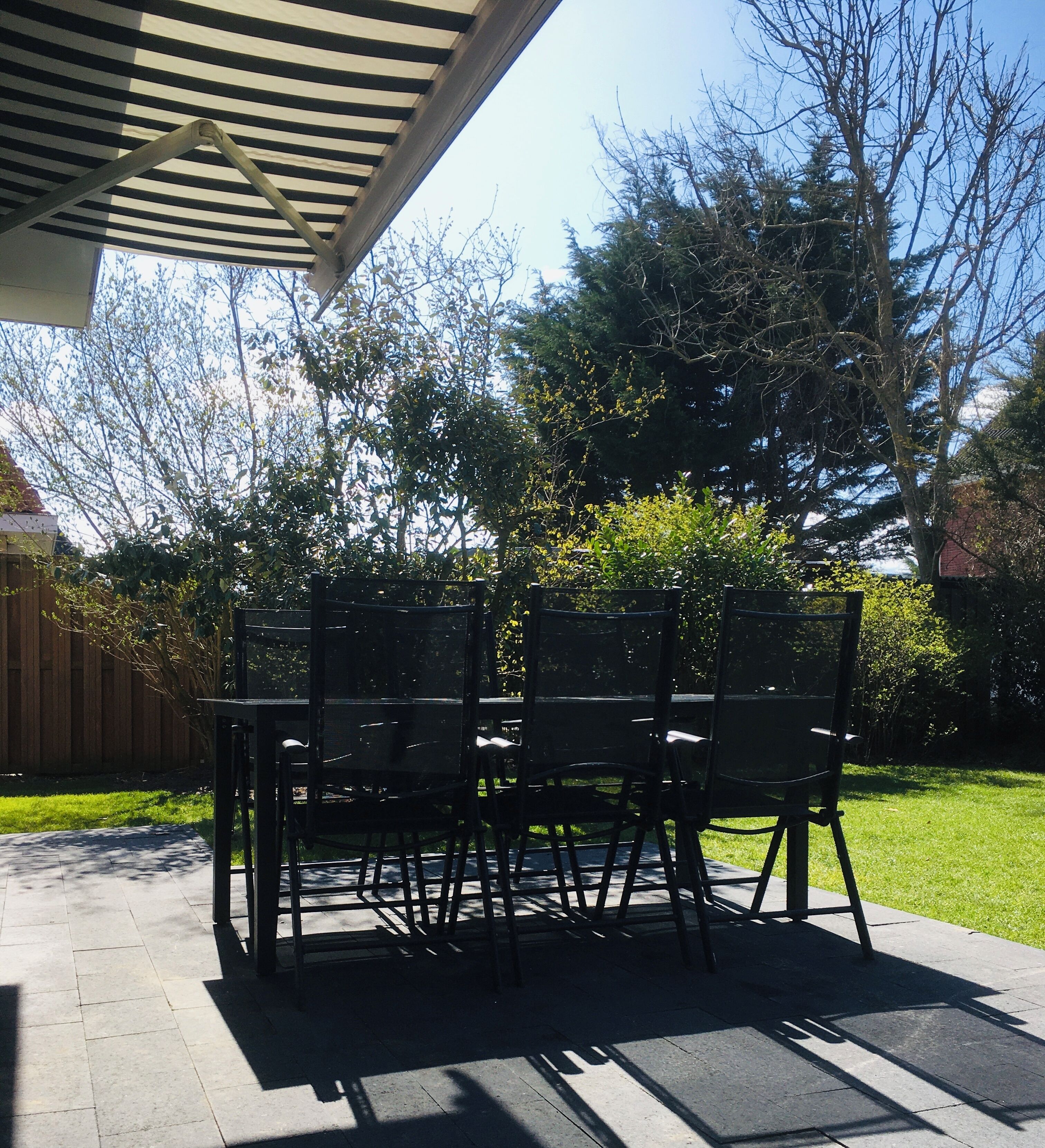 An outdoor patio with a covered seating area, surrounded by a wooden fence and trees.