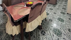 Ein Essbereich mit Tisch für vier Personen, umgeben von Stühlen, und ein Wohnbereich mit einer Couch und einem Fernseher.
