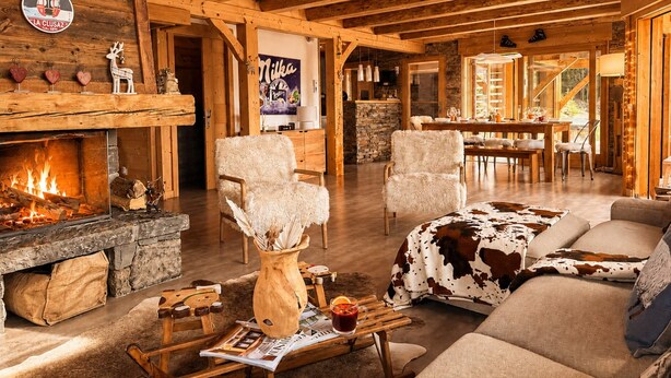 Un interior de cabaña acogedor, con chimenea, muebles de madera y una pared de piedra.