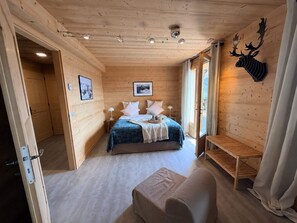 A wooden-paneled room with a bed, a bench, and a mounted deer head decoration. - Luxury Chalet "La Framboiseille" with Pool and Sauna (Manigod)