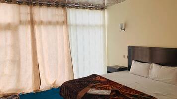Quarto de hotel com cama, mesa de cabeceira e luminária.