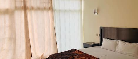 Una habitación de hotel con una cama, una mesita de noche y un aplique de pared.