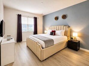 Ein Hotelzimmer mit einem großen Bett, Nachttischen, einem Fernseher und einem fenster mit Vorhängen.