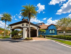 A two-story house with a covered entrance, palm trees, and a blue facade. - 6-bedroom Lakeview Pool House in Resort at Kissimmee/No Carpet/Close to Parks (Kissimmee)