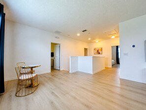 A spacious living area with a dining table and chairs, a kitchen area with a white countertop, and a hallway leading to other rooms. - 6-bedroom Lakeview Pool House in Resort at Kissimmee/No Carpet/Close to Parks (Kissimmee)