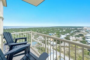 A balcony with two chairs, a view of a coastal area with houses and greenery, and a clear sky. - Beach Club Avalon Penthouse #1 - Luxury Beachfront 4BR, Views, Pool, Hot Tub (Gulf Shores)