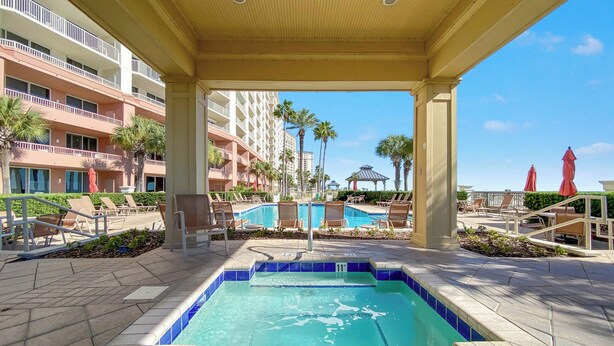 A pool area with lounge chairs, a gazebo, and a view of a hotel building. - Beach Club Avalon Penthouse #1 - Luxury Beachfront 4BR, Views, Pool, Hot Tub (Gulf Shores)