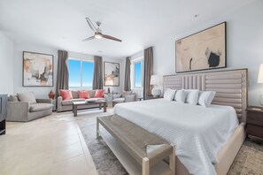 A modern hotel room with a large bed, a sofa, a desk, and a ceiling fan. - Beach Club Avalon Penthouse #1 - Luxury Beachfront 4BR, Views, Pool, Hot Tub (Gulf Shores)