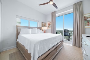 Ein Hotelzimmer mit einem großen Bett, einem Deckenventilator, einem Fenster mit Blick und einem Balkon mit einem Stuhl.