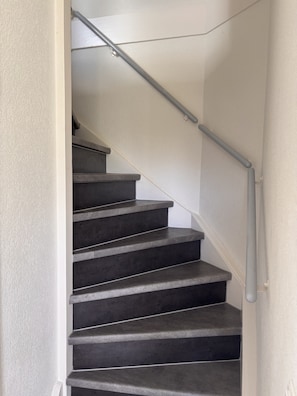 A staircase with a handrail and a textured wall. - Maralong Noordwijk (Noordwijk)