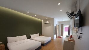 A hotel room with two beds, a desk, a TV, and a door leading to a balcony.