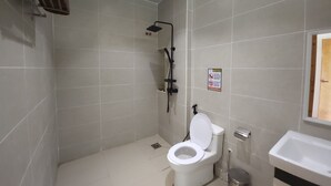 A bathroom with a toilet, a shower, and a sink.