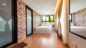 A hotel room with a checkered wall pattern, a bed, a window with curtains, and a small red object on a nightstand.