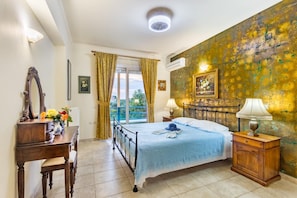 A bedroom with a bed, a dresser, a mirror, and a window with curtains. - Lefkas Blue Residence Two-bedroom Suite near to the town and close to the beach. (Lefkada)