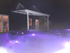 Ein Bereich mit Whirlpool, überdachter Sitzgelegenheit und einem Gebäude im Hintergrund.
