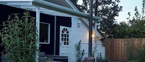 A residential property with a hot tub, a covered porch, and a wooden fence.