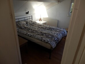 A bedroom with a bed, a nightstand, a radiator, and a window. - Family Villa With Jacuzzi & Large Garden (Balkbrug)