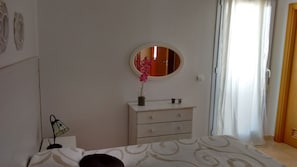 A bedroom with a bed, a dresser, a mirror, and a window with curtains. - Two-story penthouse right on the beach. Dream Subdivision (AN)