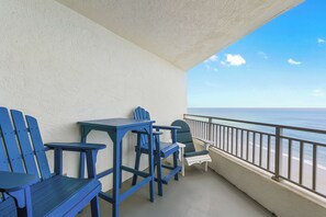 A balcony with a view of the ocean, featuring a table and two chairs. - 🏖️ Seascape Towers 1025 | Direct Oceanfront Condo | Balcony + Pool Access (New Smyrna Beach)