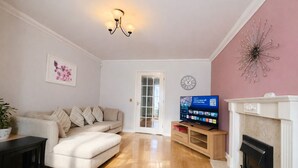 Ein Wohnzimmer mit Sofa, Fernseher, Kamin und einer Tür zu einem anderen Raum.