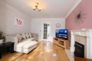 Ein Wohnzimmer mit Sofa, Fernseher, Kamin und einer Tür zu einem anderen Raum.