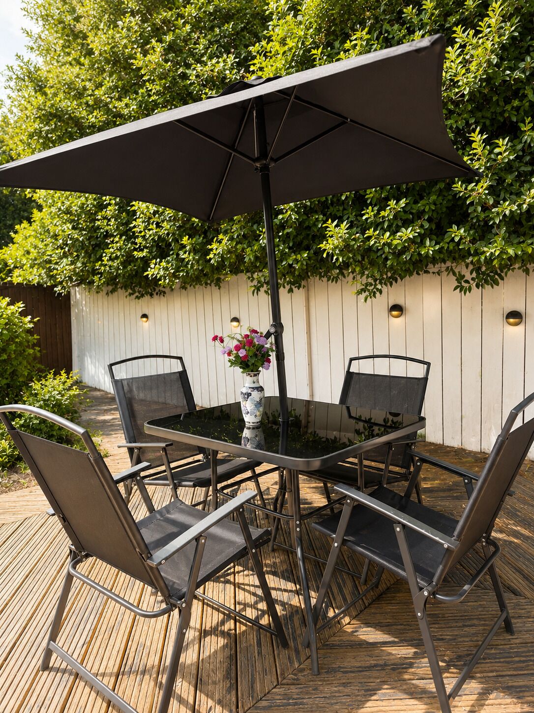 A round outdoor table with six chairs and a large umbrella.