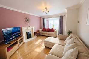 Ein Wohnzimmer mit Fernseher, einer Couch, einem Kamin und einem Wandbild.