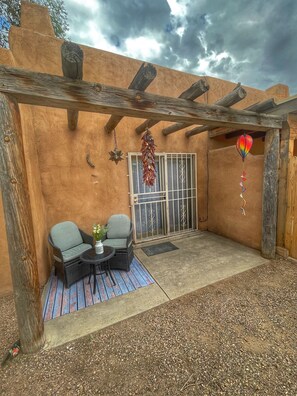 A patio area with a wooden pergola, two wicker chairs, a small round table, and a decorative hanging ornament. - Spacious two bedroom, two bathroom townhome in the heart of Albuquerque (Albuquerque)