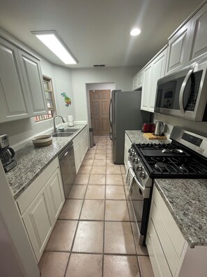 A kitchen with white cabinets, a stainless steel refrigerator, a microwave, a stove, and a sink. - Spacious two bedroom, two bathroom townhome in the heart of Albuquerque (Albuquerque)