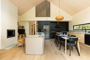 A modern kitchen with a dining area, a TV, and a sofa. - Pamyland : A chic nature getaway by the water (Saint-Alphonse-Rodriguez)