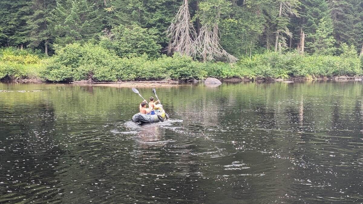 Eine Gruppe von Menschen in einem Kanu auf einem ruhigen Fluss, umgeben von dichtem Wald.