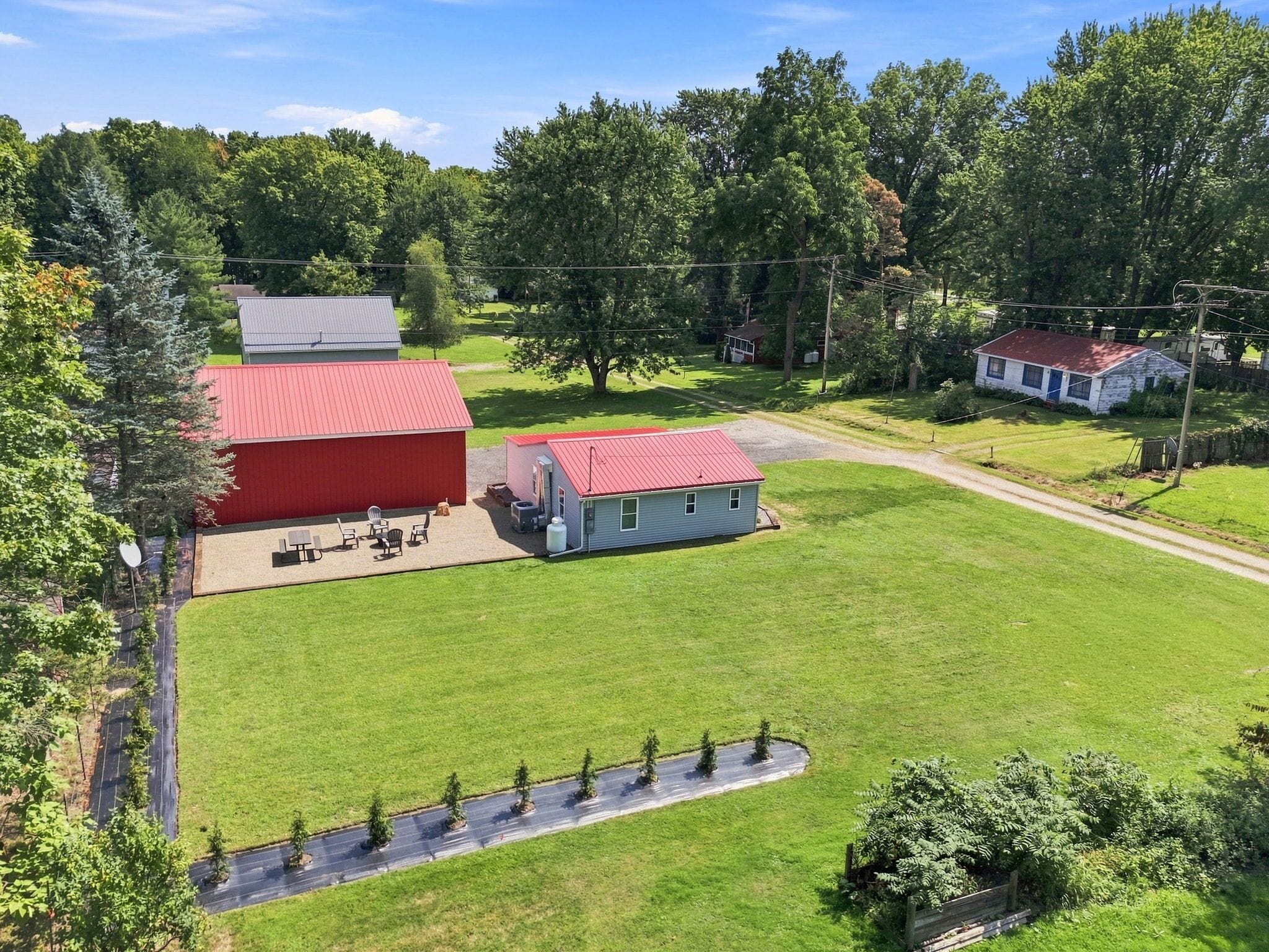 A large red barn with a small attached structure, surrounded by a well-maintained lawn and trees.