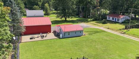 A large red barn with a small attached structure, surrounded by a well-maintained lawn and trees.